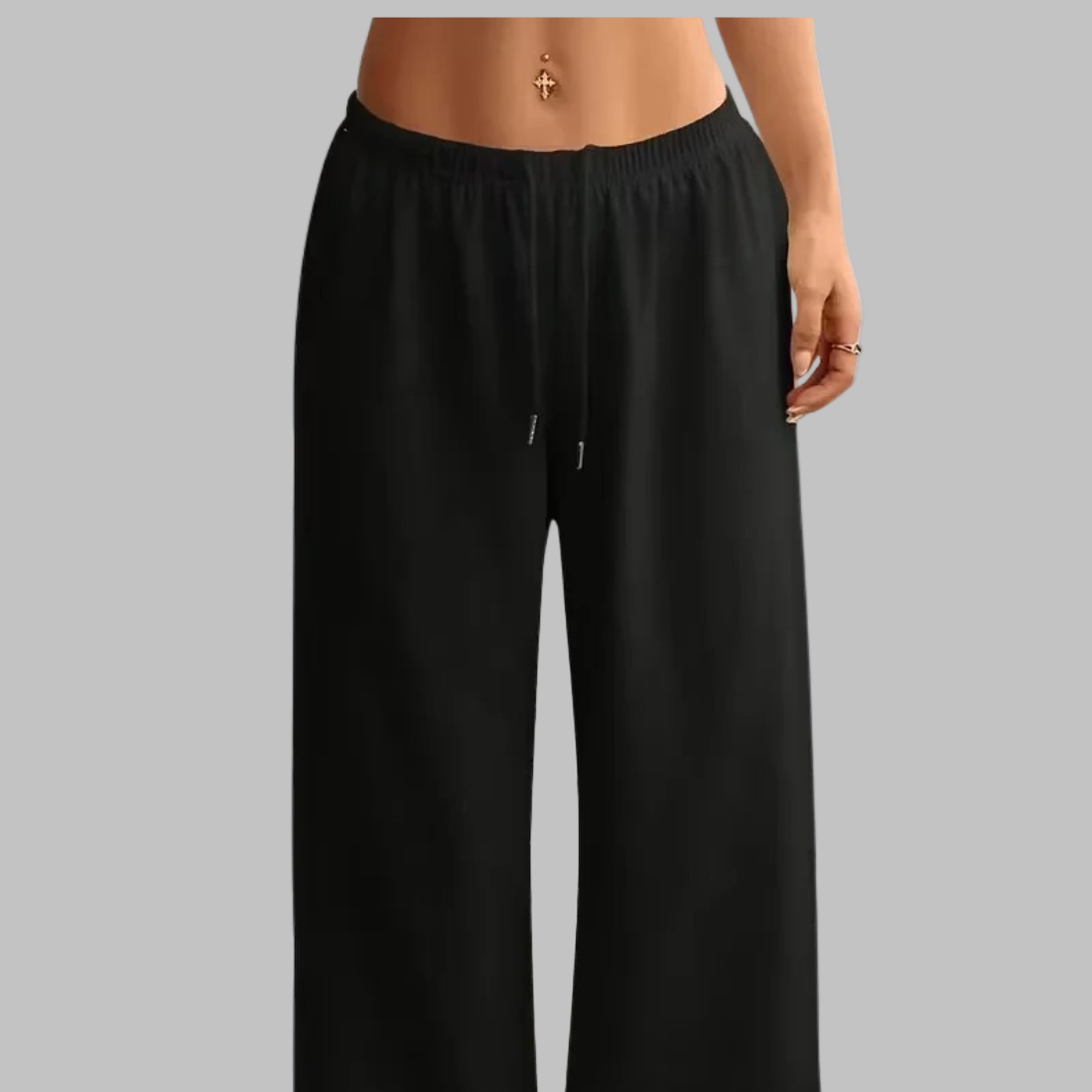 Dark blue, very wide-legged, baggy trousers with a drawstring waist, worn with a black long-sleeved crop top and black and white sneakers.